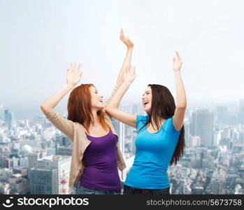 happiness, friendship and people concept - smiling teenage girls having fun over city background