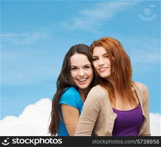 happiness, friendship and people concept - smiling teenage girls hugging over blue sky and cloud background