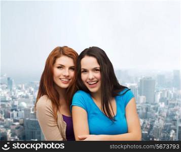 happiness, friendship and people concept - smiling teenage girls hugging over city background