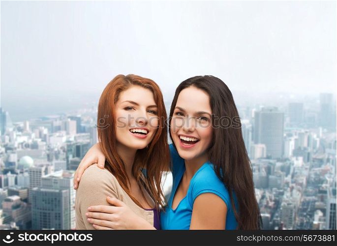 happiness, friendship and people concept - smiling teenage girls hugging over city background