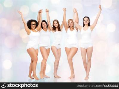 happiness, friendship, beauty, body positive and people concept - group of happy different women in white underwear with raised arms celebrating victory over holidays lights background