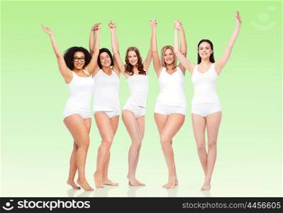 happiness, friendship, beauty, body positive and people concept - group of happy different women in white underwear with raised arms celebrating victory over green natural background
