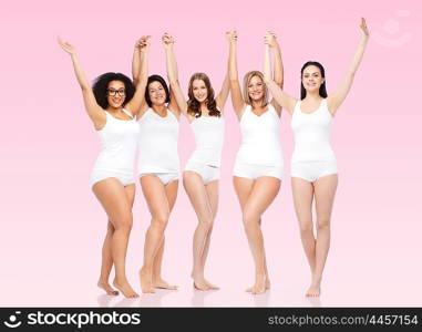 happiness, friendship, beauty, body positive and people concept - group of happy different women in white underwear with raised arms celebrating victory over pink background