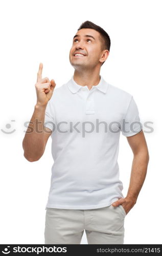 happiness, gesture and people concept - smiling man pointing finger up