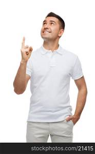 happiness, gesture and people concept - smiling man pointing finger up