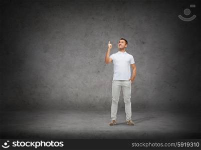 happiness, gesture and people concept - smiling man pointing finger up over concrete background