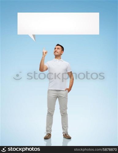 happiness, gesture and people concept - smiling man pointing finger up to white blank text bubble over blue background