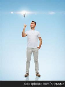 happiness, gesture and people concept - smiling man pointing finger up to lighting bulb over blue background