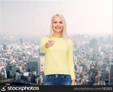 happiness, gesture and people concept - smiling woman pointing finger at you