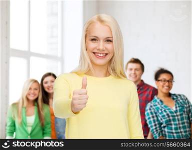 happiness, gesture and people concept - smiling young woman in casual clothes showing thumbs up