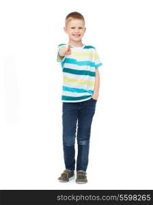 happiness, gesture, childhood and people concept - smiling little boy in casual clothes pointing his finger at you