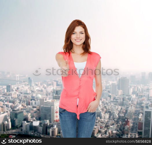 happiness, gesture, city life and people concept - smiling teenage girl in casual clothes showing thumbs up over city background