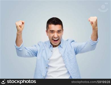 happiness, gesture, emotions, joy and people concept - happy laughing man with raised hands over gray background