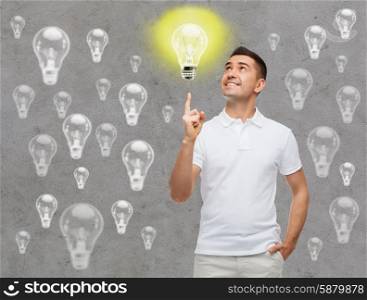 happiness, gesture, idea, inspiration and people concept - smiling man pointing finger up lighting bulb over gray background