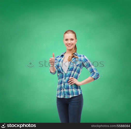 happiness, gesutre and people concept - smiling young woman in casual clothes showing thumbs up on green board background