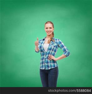 happiness, gesutre and people concept - smiling young woman in casual clothes showing thumbs up on green board background