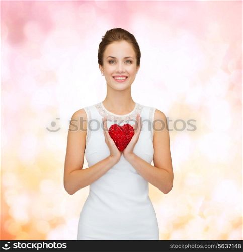 happiness, health, charity and love concept - smiling woman in white dress with red heart over pink lights background