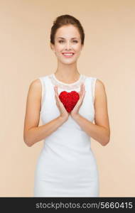 happiness, health, charity and love concept - smiling woman in white dress with red heart over beige background