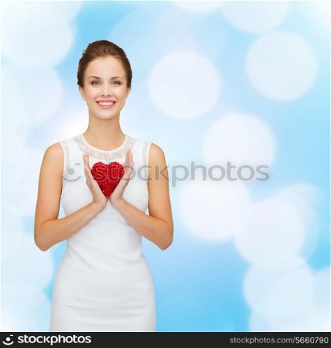 happiness, health, charity and love concept - smiling woman in white dress with red heart over blue lights background
