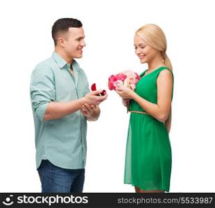 happiness, holidays, celebration and couple concept - smiling couple with flower bouquet and ring in a box