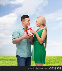 happiness, holidays, celebration and couple concept - smiling couple with gift box