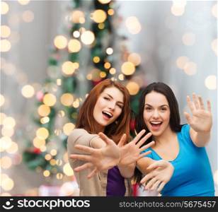happiness, holidays, friendship and people concept - smiling teenage girls having fun over christmas tree background
