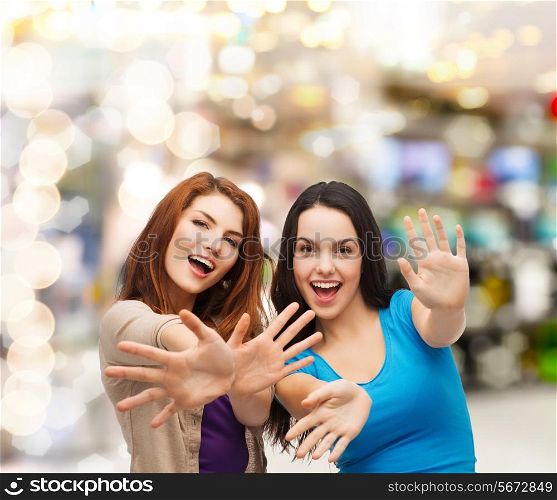 happiness, holidays, friendship and people concept - smiling teenage girls having fun over lights background