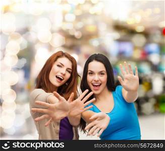 happiness, holidays, friendship and people concept - smiling teenage girls having fun over lights background
