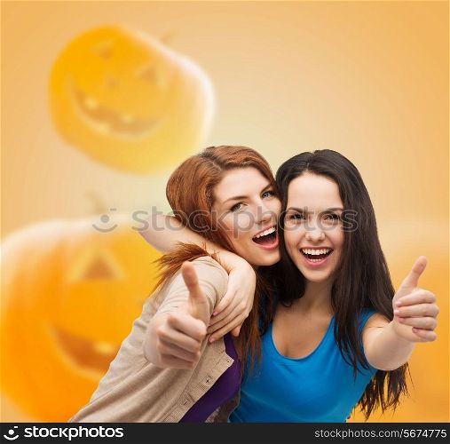 happiness, holidays, friendship, gesture and people concept - smiling teenage girls showing thumbs up over halloween pumpkins background