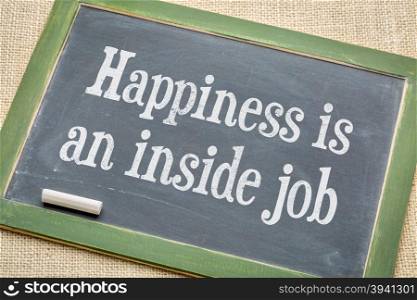 Happiness in an inside job - inspirational words on a vintage slate blackboard with a white chalk against burlap canvas