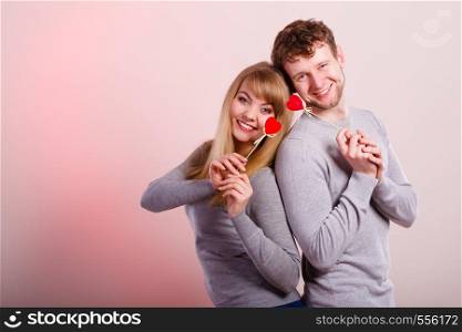 Happiness in love. Lovely charming couple smiling. Happy joyful woman and man holding little hearts on sticks. Two people with sign symbol of good relationship feelings.. Lovely happy couple with hearts.