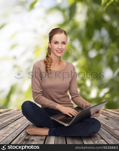 happiness, internet, technology and people concept - smiling young woman sitting on floor with laptop computer