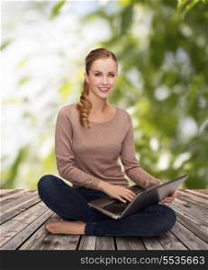 happiness, internet, technology and people concept - smiling young woman sitting on floor with laptop computer