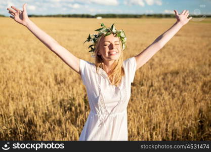 happiness, nature, summer holidays, vacation and people concept - smiling young woman in wreath of flowers and white dress on cereal field