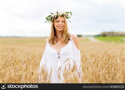 happiness, nature, summer holidays, vacation and people concept - smiling young woman in wreath of flowers on cereal field