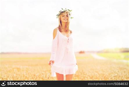 happiness, nature, summer holidays, vacation and people concept - smiling young woman in wreath of flowers and white dress on cereal field. happy young woman in flower wreath on cereal field. happy young woman in flower wreath on cereal field