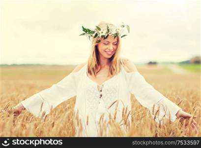 happiness, nature, summer holidays, vacation and people concept - smiling young woman in wreath of flowers on cereal field. happy young woman in flower wreath on cereal field