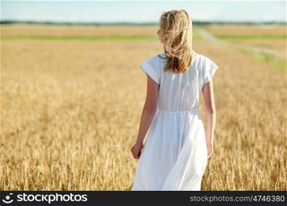 happiness, nature, summer holidays, vacation and people concept - young woman in white dress on cereal field