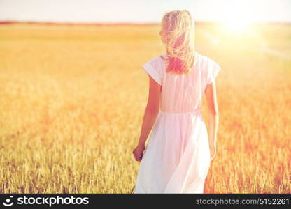 happiness, nature, summer holidays, vacation and people concept - young woman in white dress on cereal field. young woman in white dress on cereal field