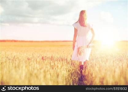 happiness, nature, summer holidays, vacation and people concept - young woman with cereal spikelets walking on field. young woman with cereal spikelets walking on field