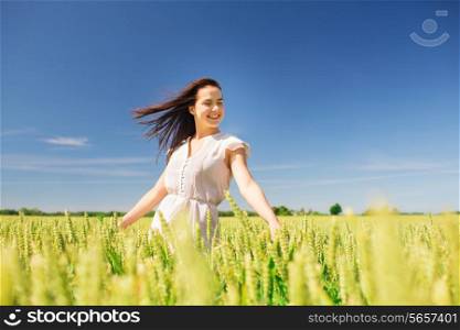 happiness, nature, summer, vacation and people concept - smiling young woman on cereal field