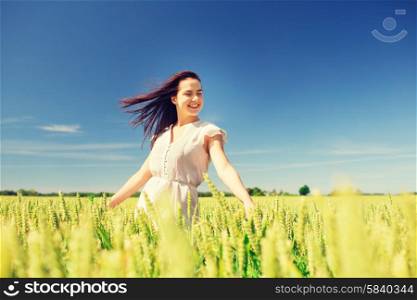 happiness, nature, summer, vacation and people concept - smiling young woman on cereal field
