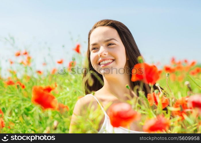 happiness, nature, summer, vacation and people concept - smiling young woman on poppy field