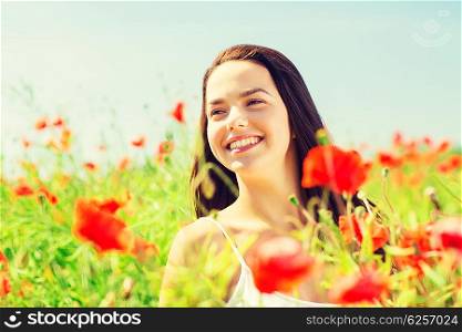 happiness, nature, summer, vacation and people concept - smiling young woman on poppy field