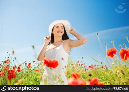 happiness, nature, summer, vacation and people concept - smiling young woman wearing straw hat on poppy field