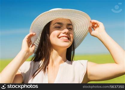 happiness, nature, summer, vacation and people concept - smiling young woman wearing straw hat in nature