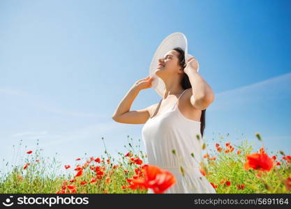 happiness, nature, summer, vacation and people concept - smiling young woman with closed eyes wearing straw hat on poppy field