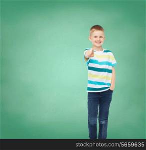 happiness, school, education, gesture and people concept - smiling boy pointing his finger at you over green board background
