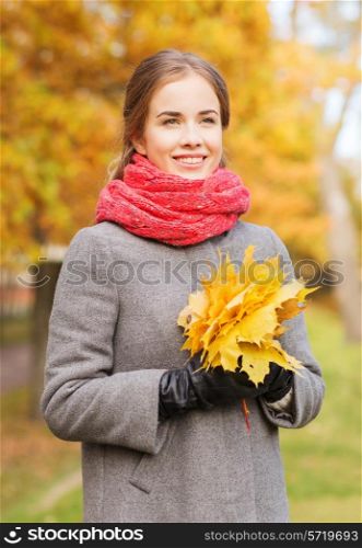 happiness, season and people concept - smiling woman with bunch of leaves in autumn park