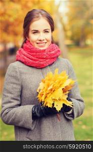 happiness, season and people concept - smiling woman with bunch of leaves in autumn park